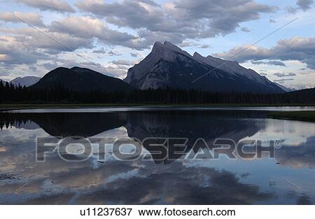 Stock Photo - Reflection of mountains on a lake, Rocky Mountains, Canada. Fotosearch
