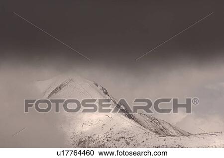 Stock Image - Cloud over Top of Snow Capped Mountain Peak, Jasper National Park, Canada. Fotosearch