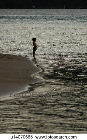 A young boy (6-8) standing on a beach, Moorea, Tahiti, French Polynesia, South Pacific View Large Photo Image Stock Photography - A young boy (6-8) standing on a beach, Moorea, Tahiti, French Polynesia, South Pacific. Fotosearch