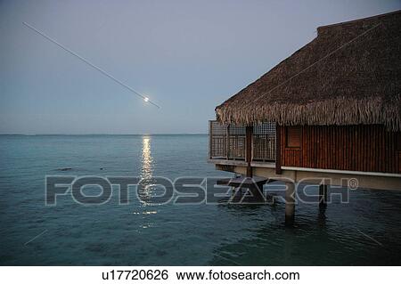 Stock Photograph - Panoramic view of the sun setting over the sea, Moorea, Tahiti, French Polynesia, South Pacific. Fotosearch