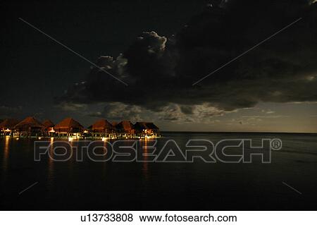 Thatched buildings on a beach lit up at night, Moorea, Tahiti, French Polynesia, South Pacific View Large Photo Image Stock Photo - Thatched buildings on a beach lit up at night, Moorea, Tahiti, French Polynesia, South Pacific. Fotosearch