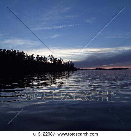 Stock Photo - Silhouette of trees by Lake of the woods, Ontario, Canada. Fotosearch