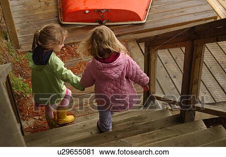 Two young girls climbing down a flight of wooden stairs View Large Photo Image Stock Image - Two young girls climbing down a flight of wooden stairs. Fotosearch