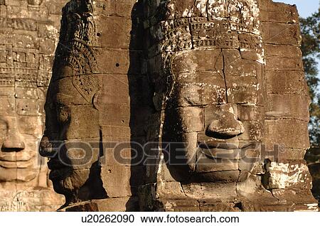 Stock Image - Stone carving of a face on wall at Khmer Kingdom palace ruins. Fotosearch