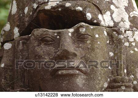 Stock Photo - Stone carving of a face on wall at Khmer Kingdom palace ruins. Fotosearch