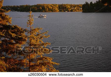 Motorboat moving through Lake of the woods, Ontario, Canada View Large Photo Image Picture - Motorboat moving through Lake of the woods, Ontario, Canada. Fotosearch
