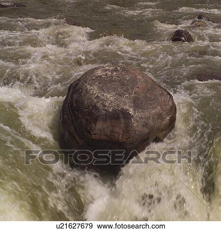 Rapids flowing around a boulder View Large Photo Image Stock Photo - Rapids flowing around a boulder. Fotosearch