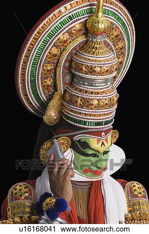 Stock Image - Close-up of a Kathakali dance performer talking on a mobile phone. Fotosearch