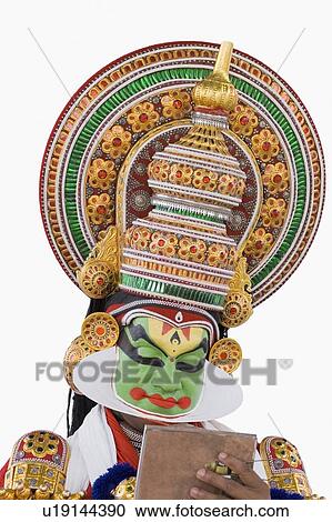 Stock Image - Close-up of a Kathakali dance performer holding a mirror. Fotosearch