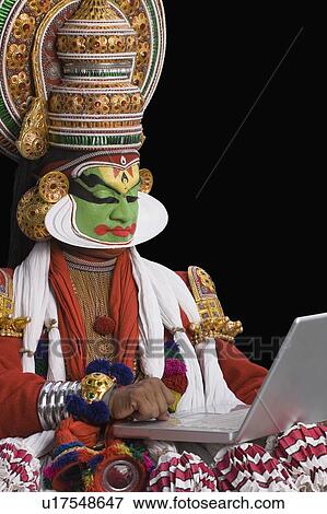Stock Photo - Close-up of a Kathakali dance performer using a laptop. Fotosearch