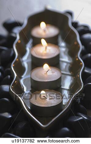 Close-up of four aromatherapy candles burning in a tray with black pebbles View Large Photo Image Stock Image - Close-up of four aromatherapy candles burning in a tray with black pebbles. Fotosearch