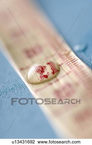 Stock Image - Close-up of water droplet on a tape measure. Fotosearch