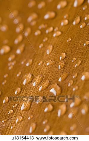 Stock Image - Close-up of water drops on a brown surface. Fotosearch