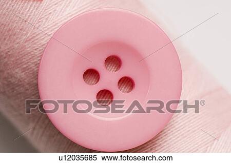 Stock Photography - Close-up of a pink button with a spool of pink thread. Fotosearch