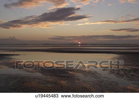 Stock Image - Sunset over tide pools and mud flats Donna Nook, Lincolnshire, UK. Fotosearch