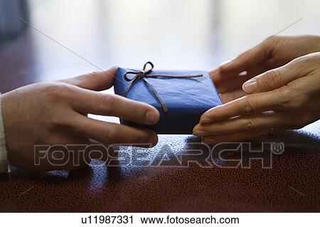 Stock Image - Close-up Image of a Present and Hands, High Angle View. Fotosearch
