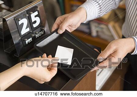Stock Photograph - Hand Placing a Credit Card on a Tray, High Angle View, Differential Focus. Fotosearch