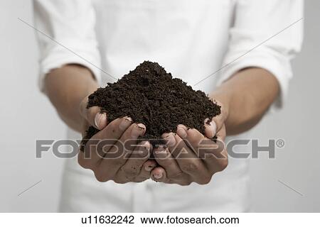 Stock Image - Heap of soil in person's hands (mid section). Fotosearch