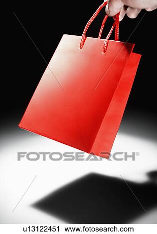 Stock Image - Person's Hand Holding Red Shopping Bag. Fotosearch
