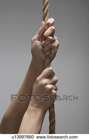Stock Image - Woman climbing rope (close-up, focus on hands). Fotosearch