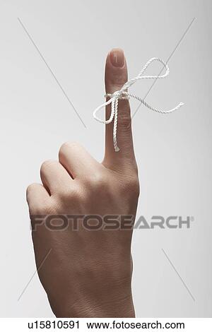 Stock Image - String tied on woman's index finger (close-up). Fotosearch