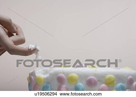 Picture - Woman's finger in cake (close-up). Fotosearch