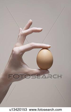 Stock Image - Woman's hand holding egg (close-up). Fotosearch