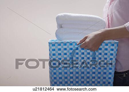 Picture - Young woman carrying laundry basket (midsection). Fotosearch