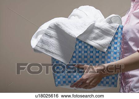 Stock Photograph - Young woman carrying laundry basket (midsection). Fotosearch