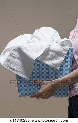 Stock Photography - Young woman carrying laundry basket (midsection). Fotosearch