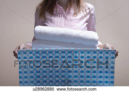 Stock Photography - Young woman carrying laundry basket (midsection). Fotosearch