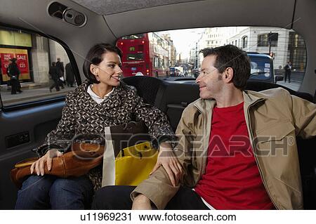 Stock Image - Couple in London taxi with bags. Fotosearch