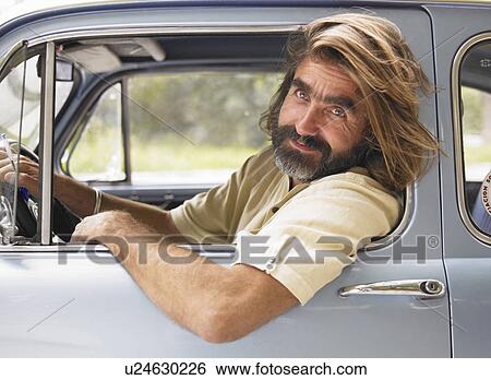 Stock Photograph - Mature man driving car, leaning out of open window, portrait. Fotosearch