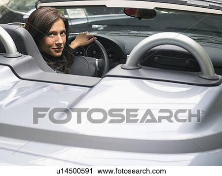 Stock Image - Woman in a convertible looking back at camera.. Fotosearch