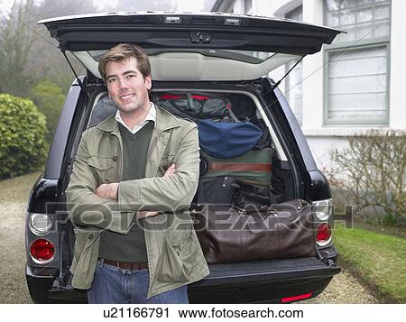 Young man in front of packed car View Large Photo Image Stock Image - Young man in front of packed car. Fotosearch