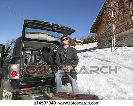 Stock Photo - Young man in front of packed car. Fotosearch