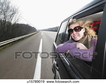 Young woman leaning out of car window View Large Photo Image Stock Photo - Young woman leaning out of car window. Fotosearch