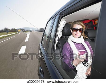 Stock Image - Young woman listening to music in car. Fotosearch