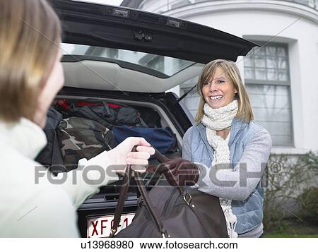 Stock Image - Young women packing car. Fotosearch