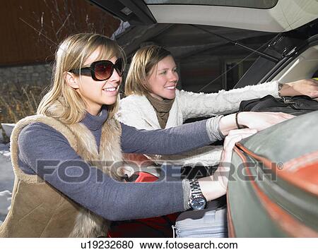 Stock Image - Young women packing car. Fotosearch