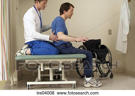 Physical Therapist Helping Wheelchair Bound Man Stock Photo