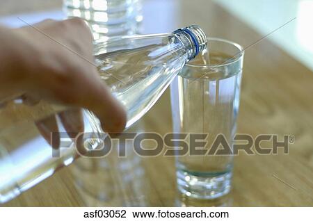 Personne Versant Eau Depuis Bouteille Dans Verre Gros Plan Banque Dimage