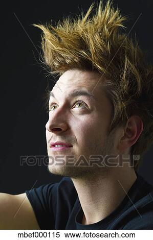 Close Up Of Young Man With Spiky Hair Against Black Background