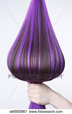 Human Hand Holding Brown Hair With Purple Highlights Against White