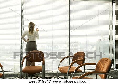 Businesswoman In Office Looking Through Blinds Stock Photo Westf Fotosearch