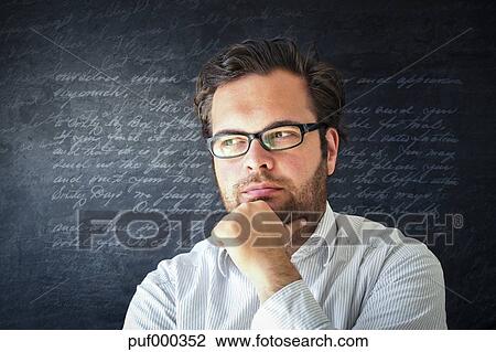 Portrait Of Pensive Man With Full Beard Wearing Glasses In Front Of Dark Background With Writings Stock Image
