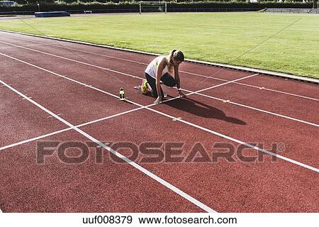 Young Woman On Tartan Track In Starting Position Stock Photo Uuf008379 Fotosearch