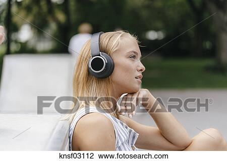 Young woman with headphones listening to music outdoors ...