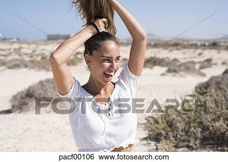 Young Woman Tying Her Hair Up Laughing Stock Photograph