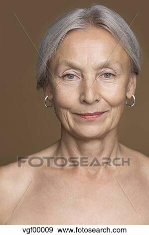 Portrait Of Naked Senior Woman With Grey Hair In Front Of Brown Background Stock Photo